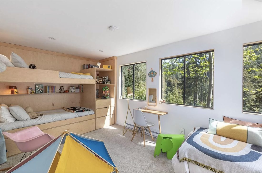 A playful children's room with built-in plywood bunk beds, a play tent, and bright furniture.